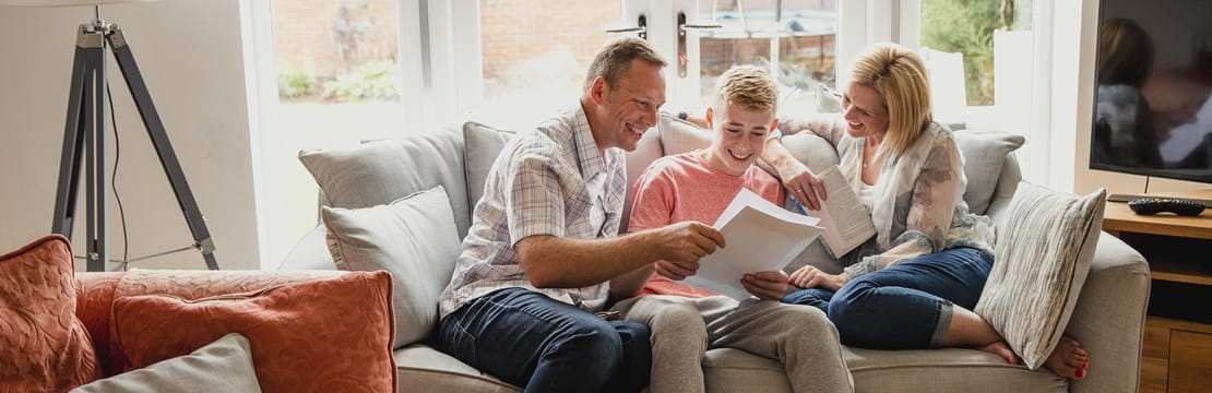A teenage boy reads his exam results with his parents.